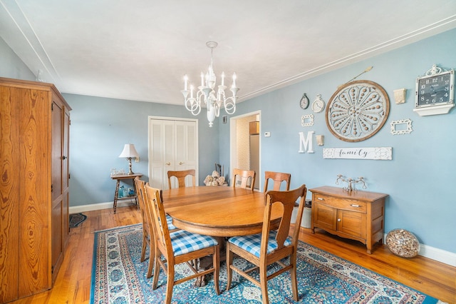 dining area featuring ornamental molding, light wood-style flooring, baseboards, and an inviting chandelier