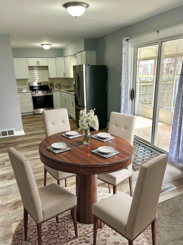 dining area featuring light wood-type flooring and visible vents