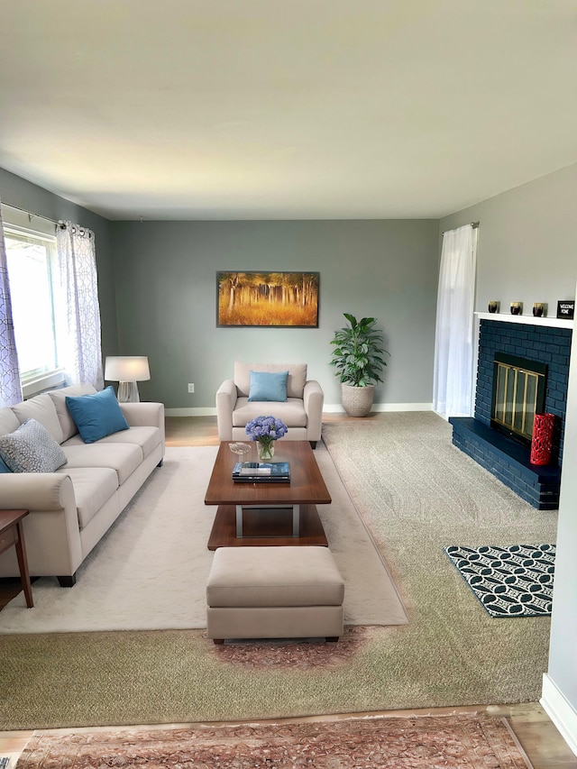 living room featuring a brick fireplace and baseboards