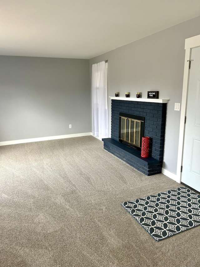 unfurnished living room featuring carpet, a fireplace, and baseboards