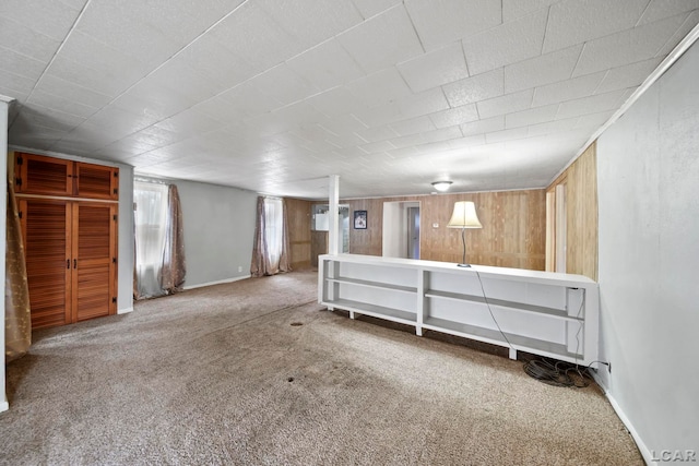 below grade area with wooden walls, baseboards, and carpet flooring