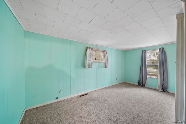 unfurnished room with carpet floors, visible vents, and baseboards