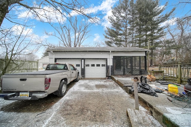 garage featuring fence and aphalt driveway