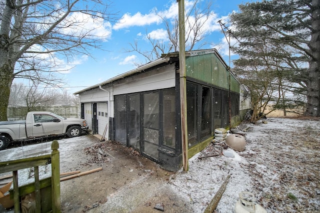 view of home's exterior featuring a sunroom and a detached garage