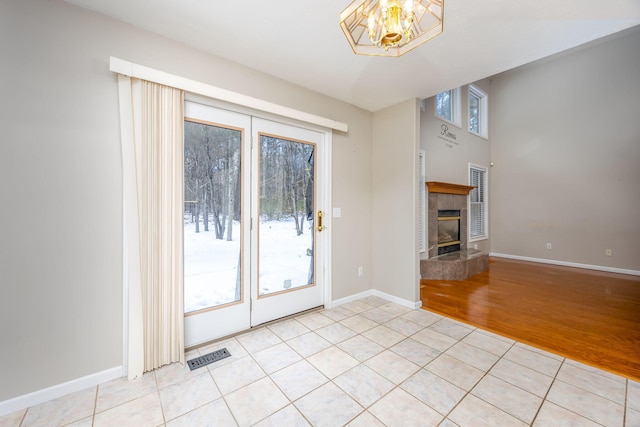 entryway with light tile patterned floors, baseboards, visible vents, and a tiled fireplace