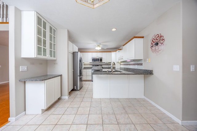 kitchen with light tile patterned floors, stainless steel appliances, decorative backsplash, glass insert cabinets, and a peninsula