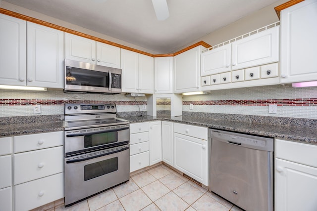 kitchen featuring light tile patterned floors, backsplash, appliances with stainless steel finishes, a ceiling fan, and white cabinets