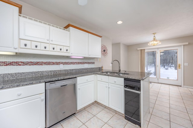 kitchen with a sink, a peninsula, backsplash, and stainless steel dishwasher