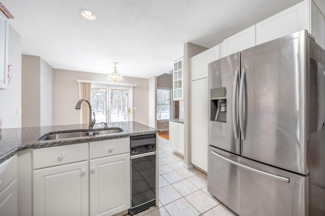 kitchen featuring white cabinets, light tile patterned flooring, a sink, and stainless steel fridge with ice dispenser