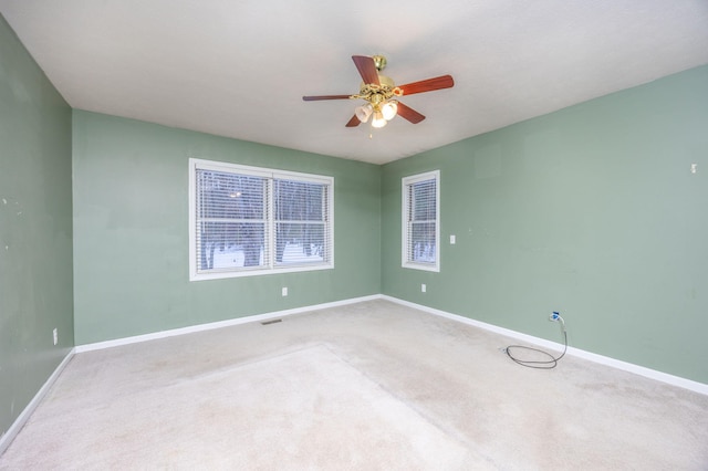 carpeted empty room featuring a ceiling fan, visible vents, and baseboards