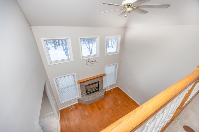 living area featuring visible vents, vaulted ceiling, ceiling fan, a tile fireplace, and baseboards