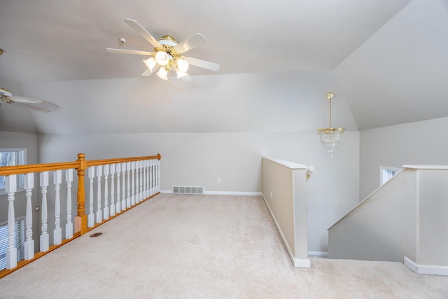 bonus room featuring ceiling fan with notable chandelier, carpet floors, lofted ceiling, and baseboards