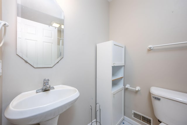 bathroom featuring toilet, a sink, and visible vents