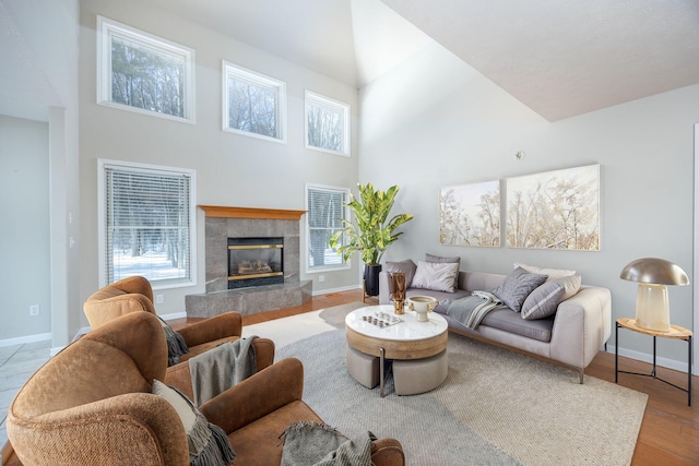 living area featuring a healthy amount of sunlight, a fireplace, baseboards, and wood finished floors