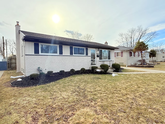 single story home featuring brick siding, fence, a chimney, and a front lawn