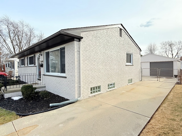 view of side of property with an outbuilding, brick siding, fence, and a garage