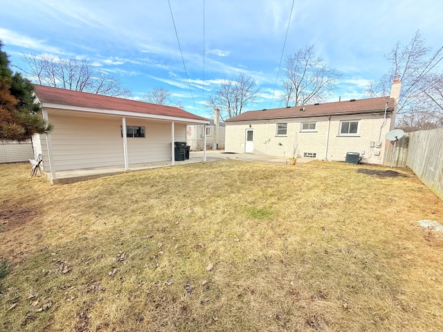 rear view of house with a patio, cooling unit, fence, a yard, and a chimney