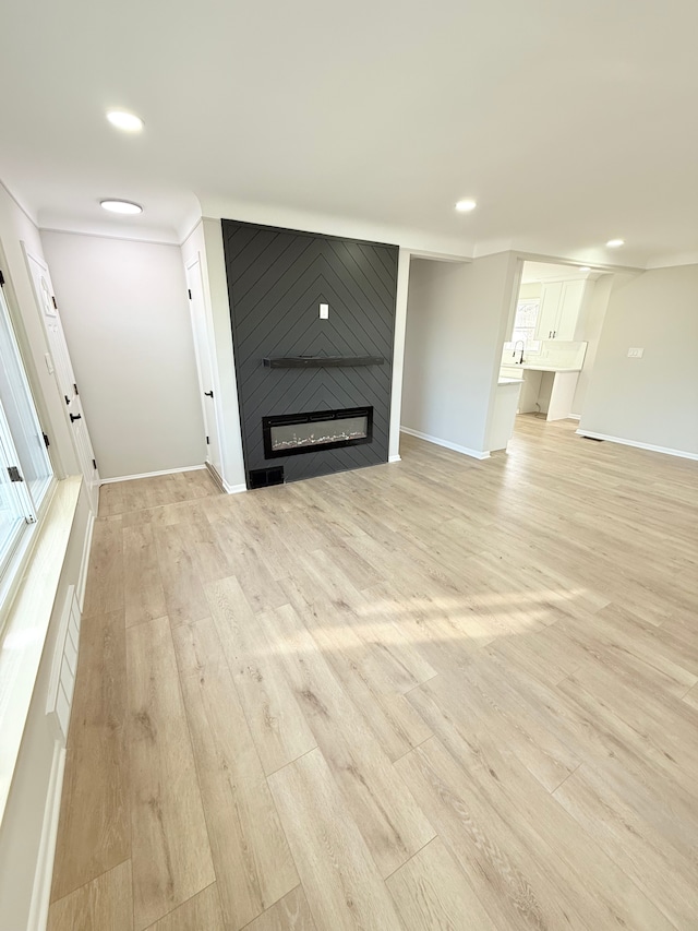 unfurnished living room with light wood-style floors, baseboards, a fireplace, and visible vents