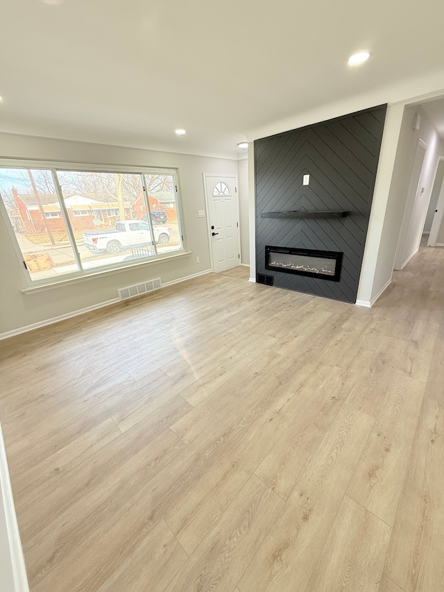 unfurnished living room featuring recessed lighting, a fireplace, wood finished floors, visible vents, and baseboards