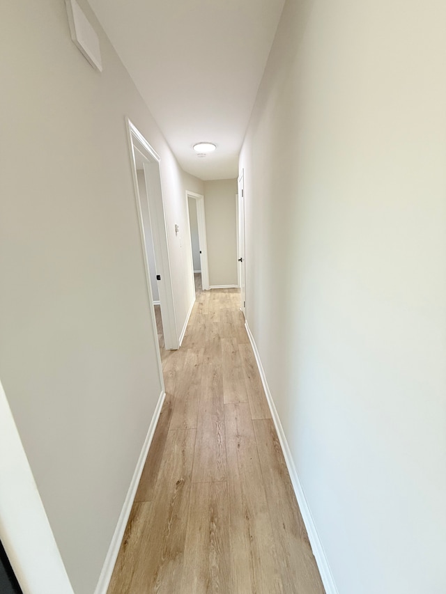 corridor featuring light wood-type flooring and baseboards