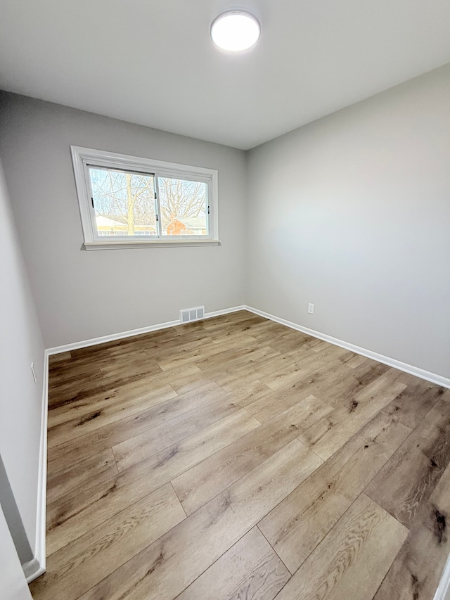 spare room with visible vents, baseboards, and wood finished floors