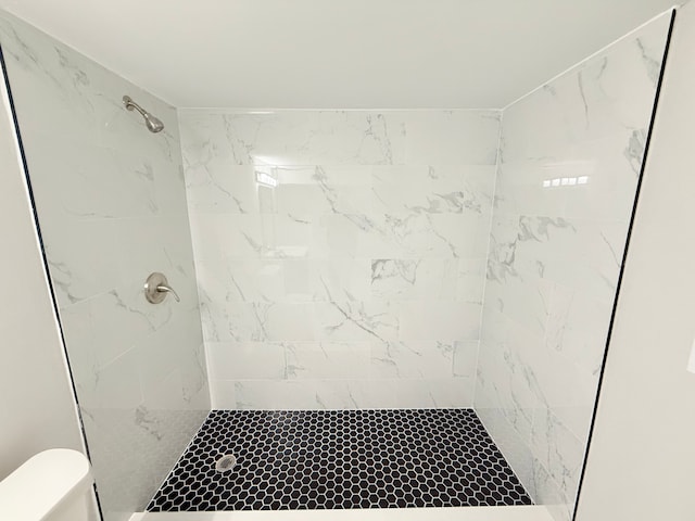 full bath with a tile shower and toilet