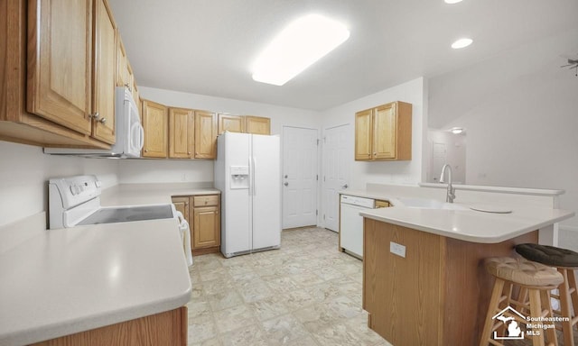 kitchen with white appliances, a breakfast bar, a peninsula, light countertops, and a sink