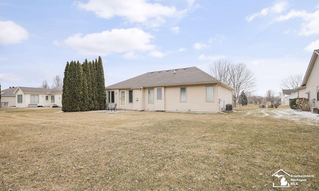 rear view of property featuring cooling unit and a lawn