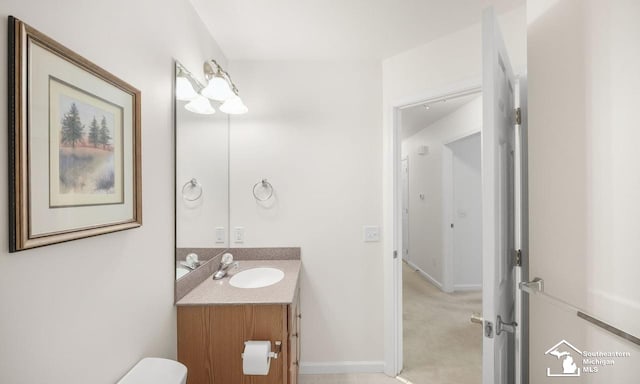 half bath featuring toilet, vanity, and baseboards