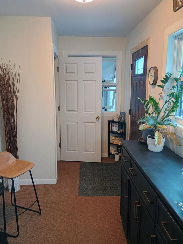 foyer entrance with dark colored carpet and baseboards