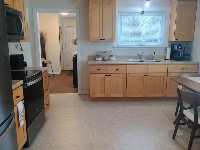 kitchen featuring light brown cabinets, light countertops, a sink, and range with electric stovetop