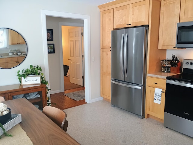 kitchen with stainless steel appliances, light brown cabinets, light countertops, and baseboards