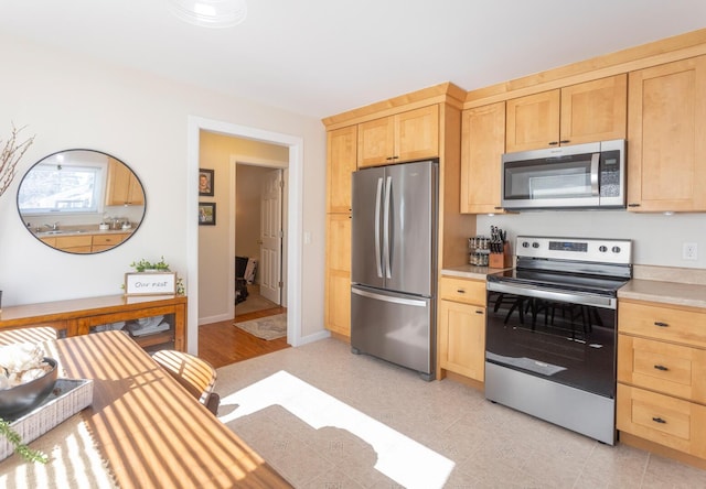 kitchen featuring stainless steel appliances, light countertops, and light brown cabinetry