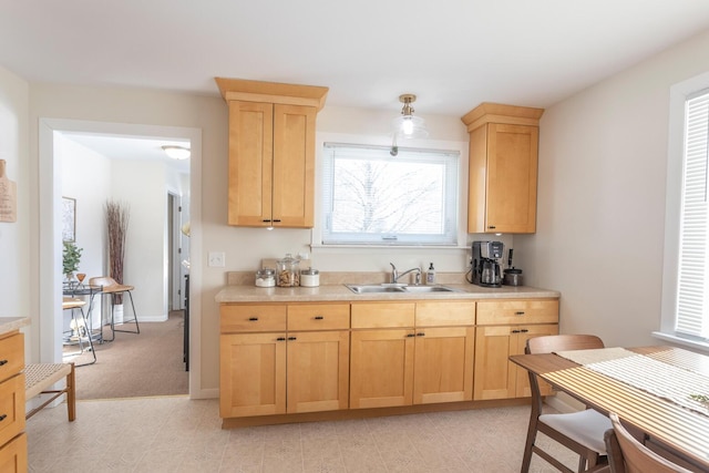 kitchen featuring light brown cabinets, light countertops, a sink, and baseboards