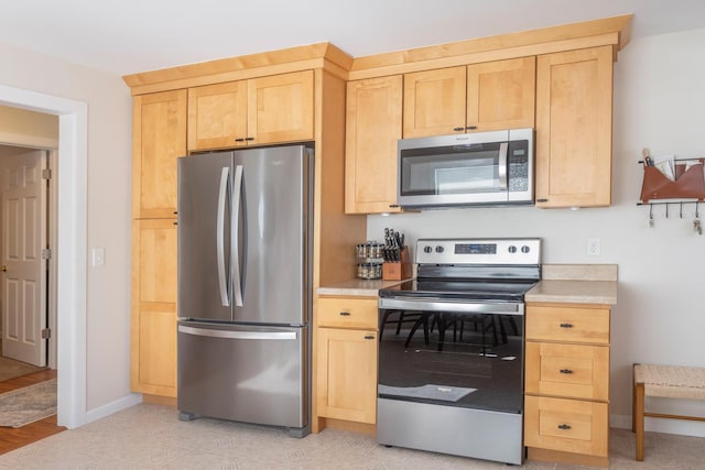 kitchen with stainless steel appliances, light brown cabinets, and light countertops