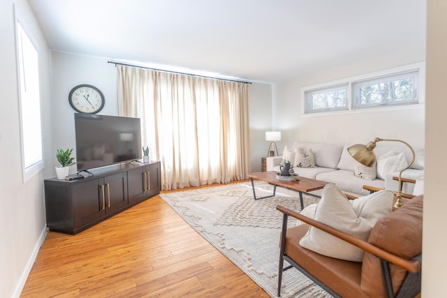 living area featuring light wood-type flooring, a healthy amount of sunlight, and baseboards