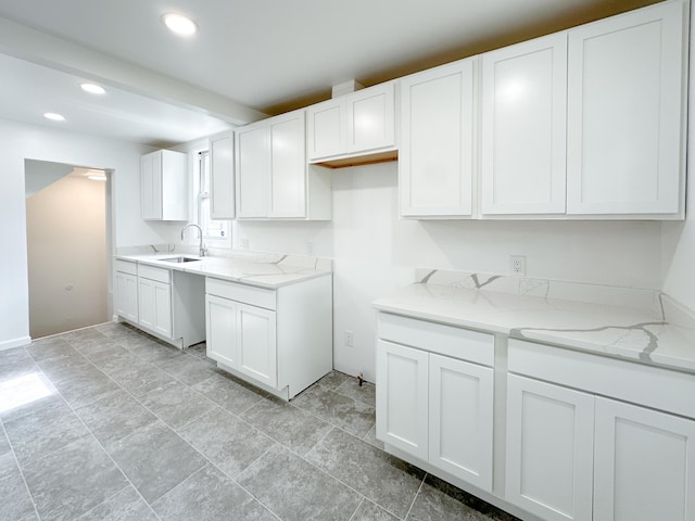 kitchen featuring light stone counters, a sink, white cabinets, and recessed lighting