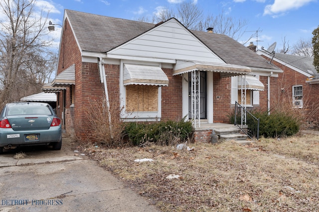 view of front of house featuring roof with shingles, concrete driveway, and brick siding