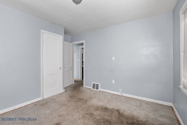 empty room featuring carpet, visible vents, and baseboards