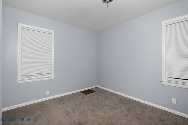 empty room with carpet, visible vents, and baseboards