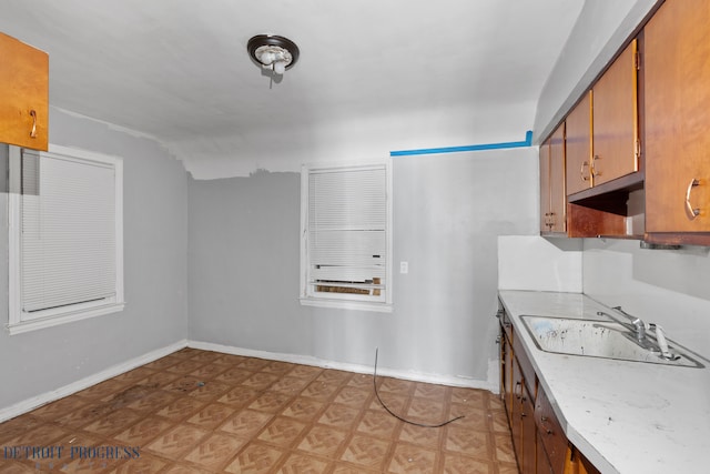 kitchen with a sink, baseboards, light countertops, brown cabinets, and light floors