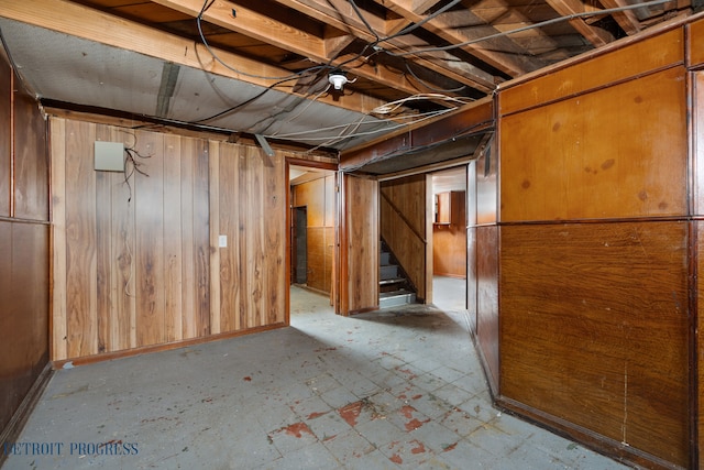 unfinished basement featuring wooden walls and stairway