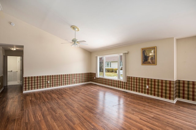 unfurnished room featuring lofted ceiling, a wainscoted wall, wallpapered walls, and wood finished floors