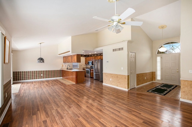 unfurnished living room with a wainscoted wall, dark wood finished floors, visible vents, a ceiling fan, and high vaulted ceiling