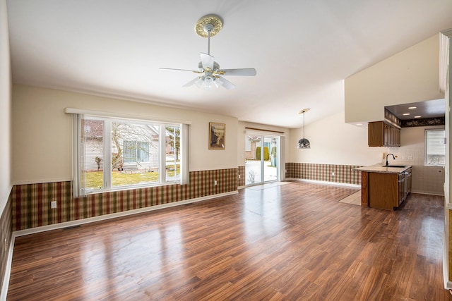 unfurnished living room with lofted ceiling, dark wood-style flooring, a sink, and wainscoting