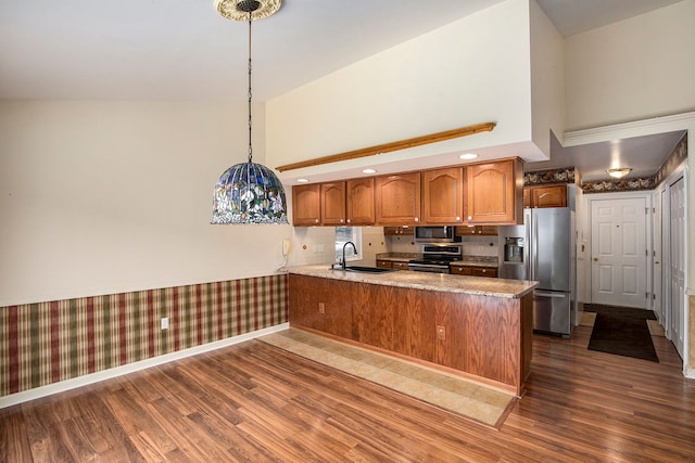 kitchen featuring brown cabinetry, a peninsula, stainless steel appliances, high vaulted ceiling, and a sink