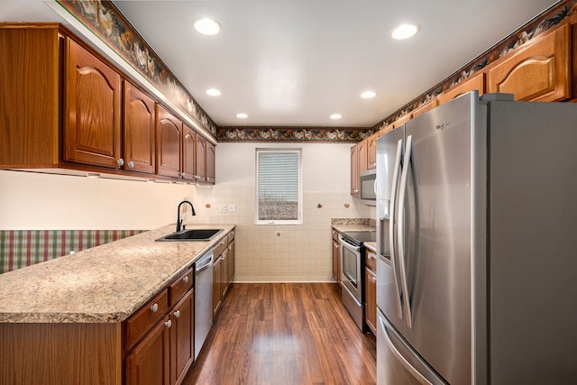 kitchen featuring appliances with stainless steel finishes, dark wood-style flooring, a sink, light countertops, and tile walls