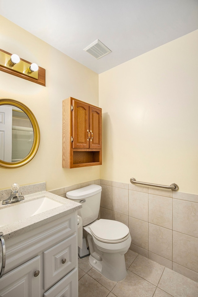 bathroom featuring tile walls, visible vents, toilet, wainscoting, and tile patterned flooring