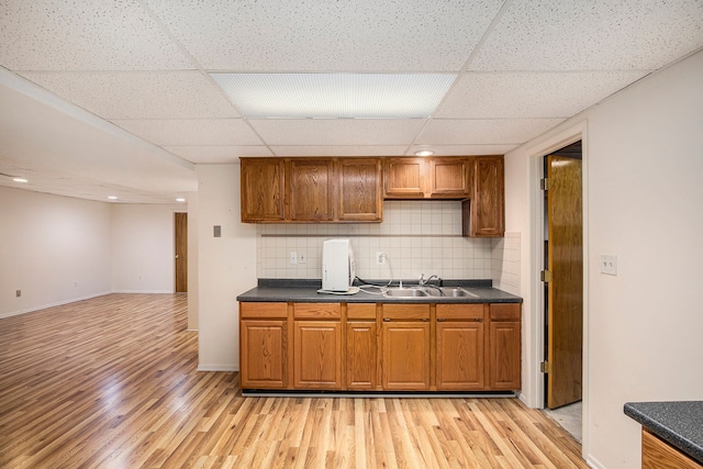 kitchen featuring tasteful backsplash, dark countertops, brown cabinets, and a sink