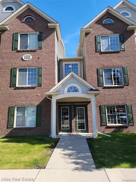 view of front of home featuring brick siding and a front yard